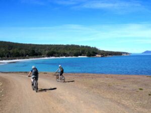 Jon and Corinne cycling on Maria Island, painted cliffs in the background