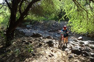 Jude pushing her bike through a rocky creek bed