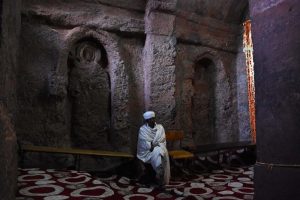 a monk in silent reflection between some of the seven saints carved in the walls of Bete Golgotha - the only church in Lalibela where women are not allowed to enter