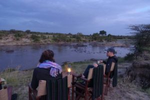 Regine and Jon enjoying sundowners at xmas, watching the hippos snort, poo and fight in the pool in the Mara River